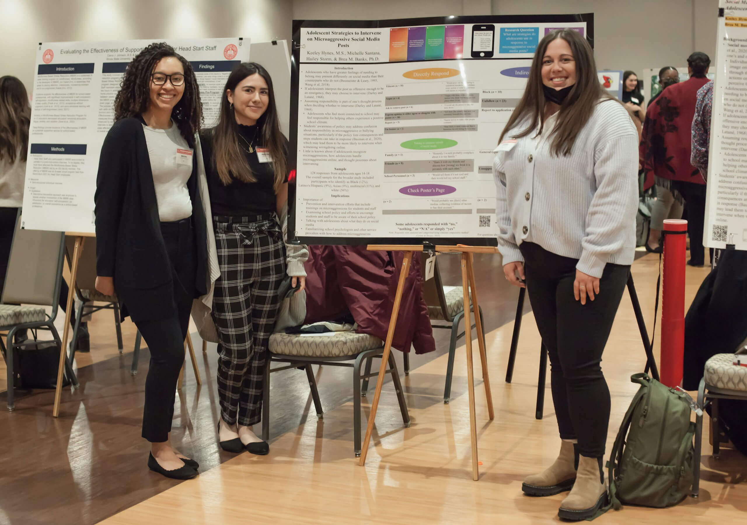 Three students displaying their research poster.